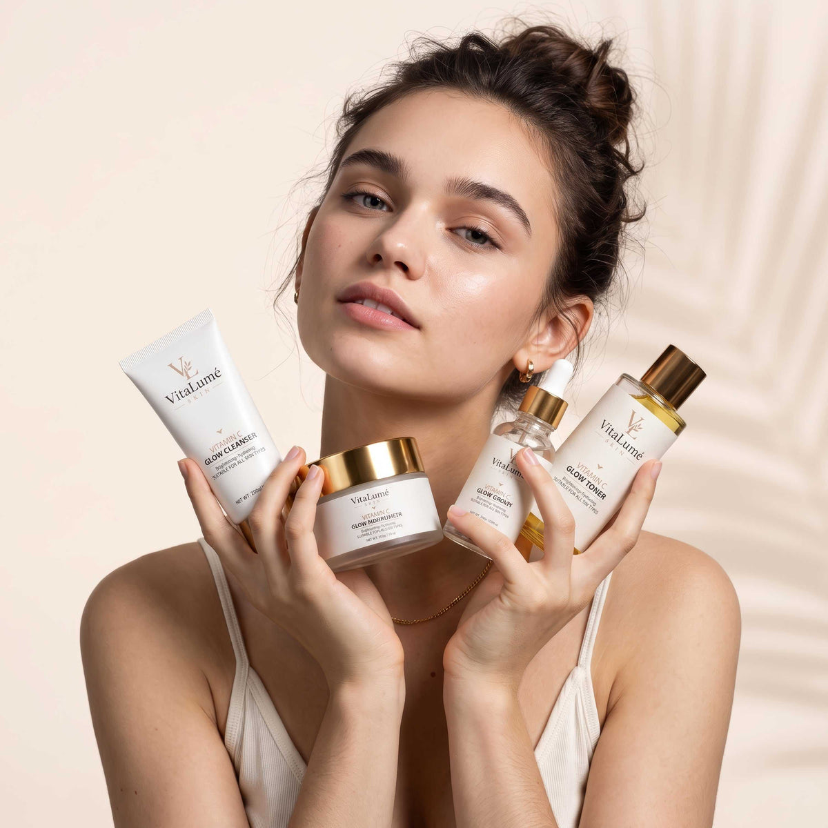 glowing skin care featuring white skincare cleanser, serum, toner and moisturizer containers with gold accents
